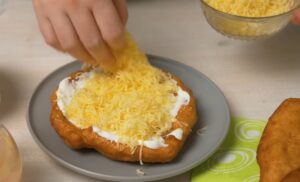 osoba filuje langoš sa pavlakom i sirom