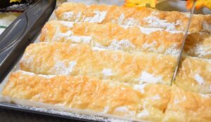 osoba seče pitu sa bundevom koja je posuta prah šećerom